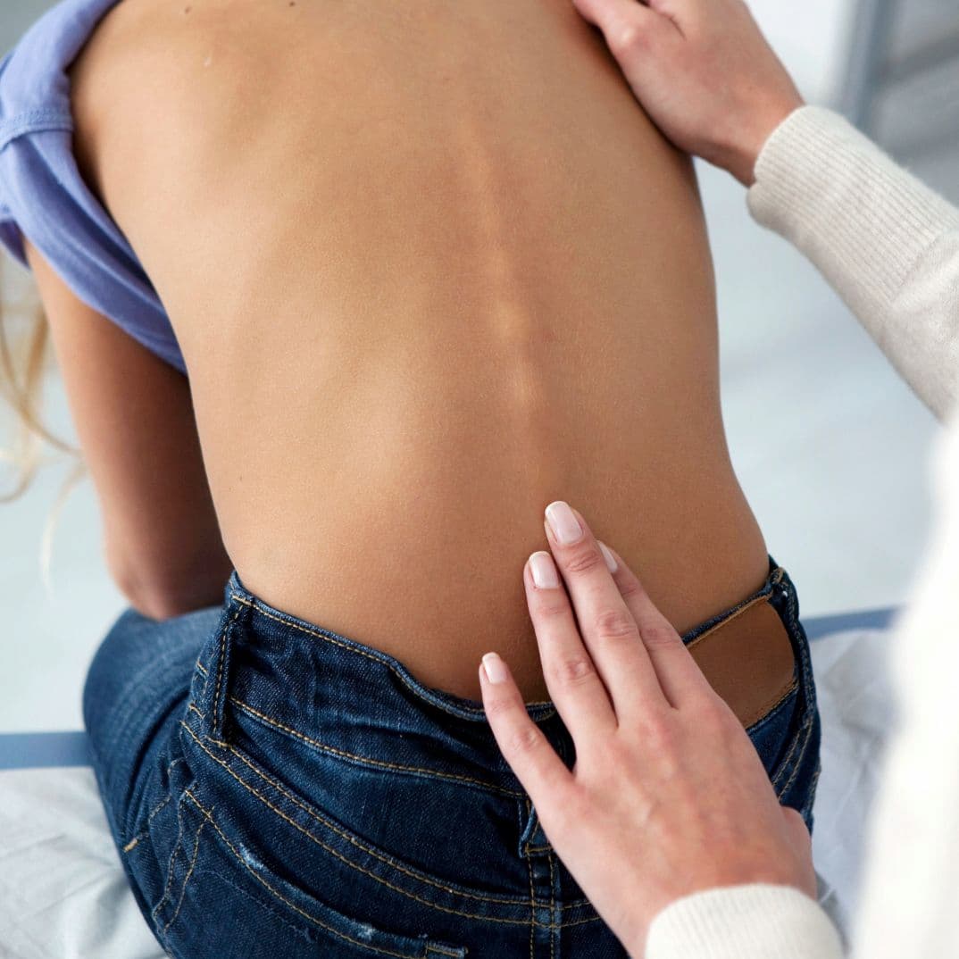Close up of child's back, as a practitioner examines their spine.