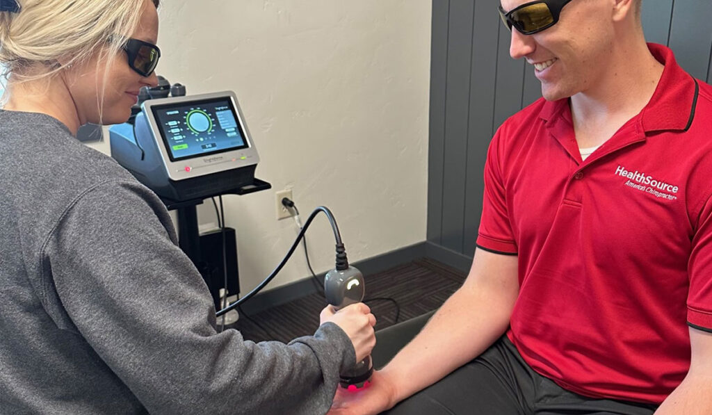 A patient receiving laser therapy treatment on their wrist and hand at HealthSource of Meridian