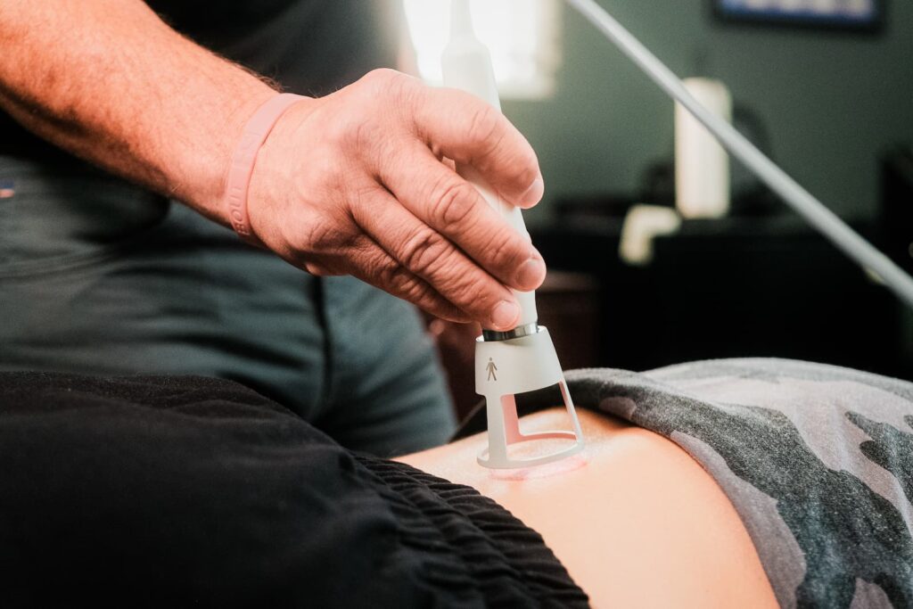 Close up of practitioner applying laser treatment to patient's lower back.