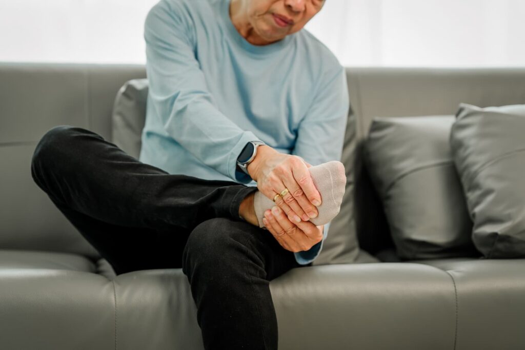 Person sits on couch, rubbing the tingles away in feet.