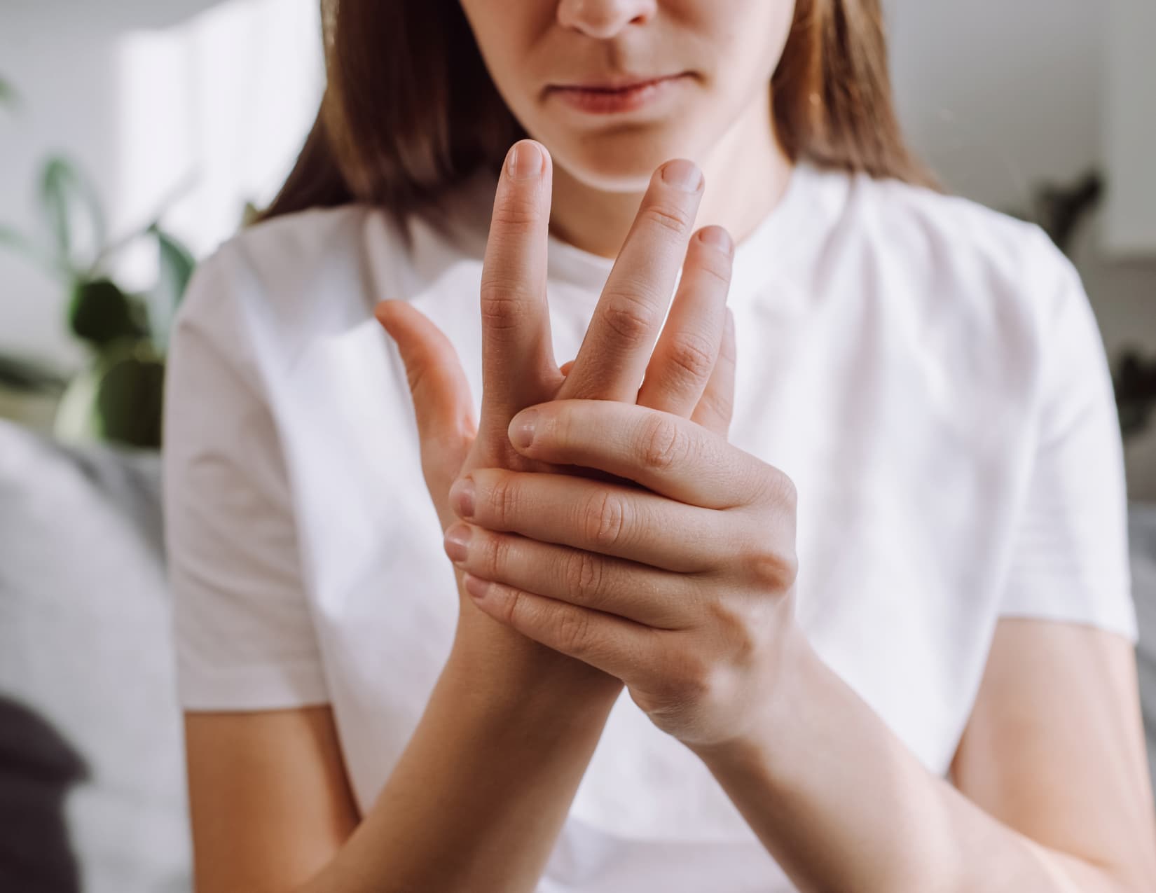 Young woman grips her right hand, rubbing away tingles.