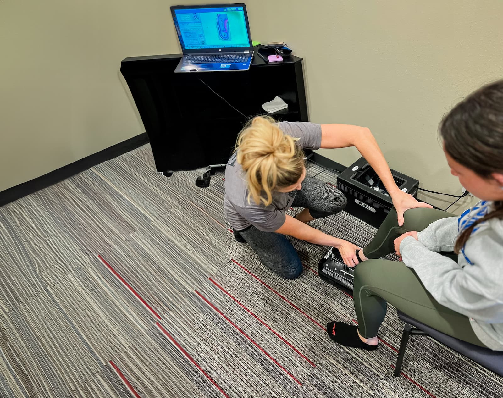 Overhead view of a practitioner pressing a patient's foot into a tool meant to take an impression of their sole.