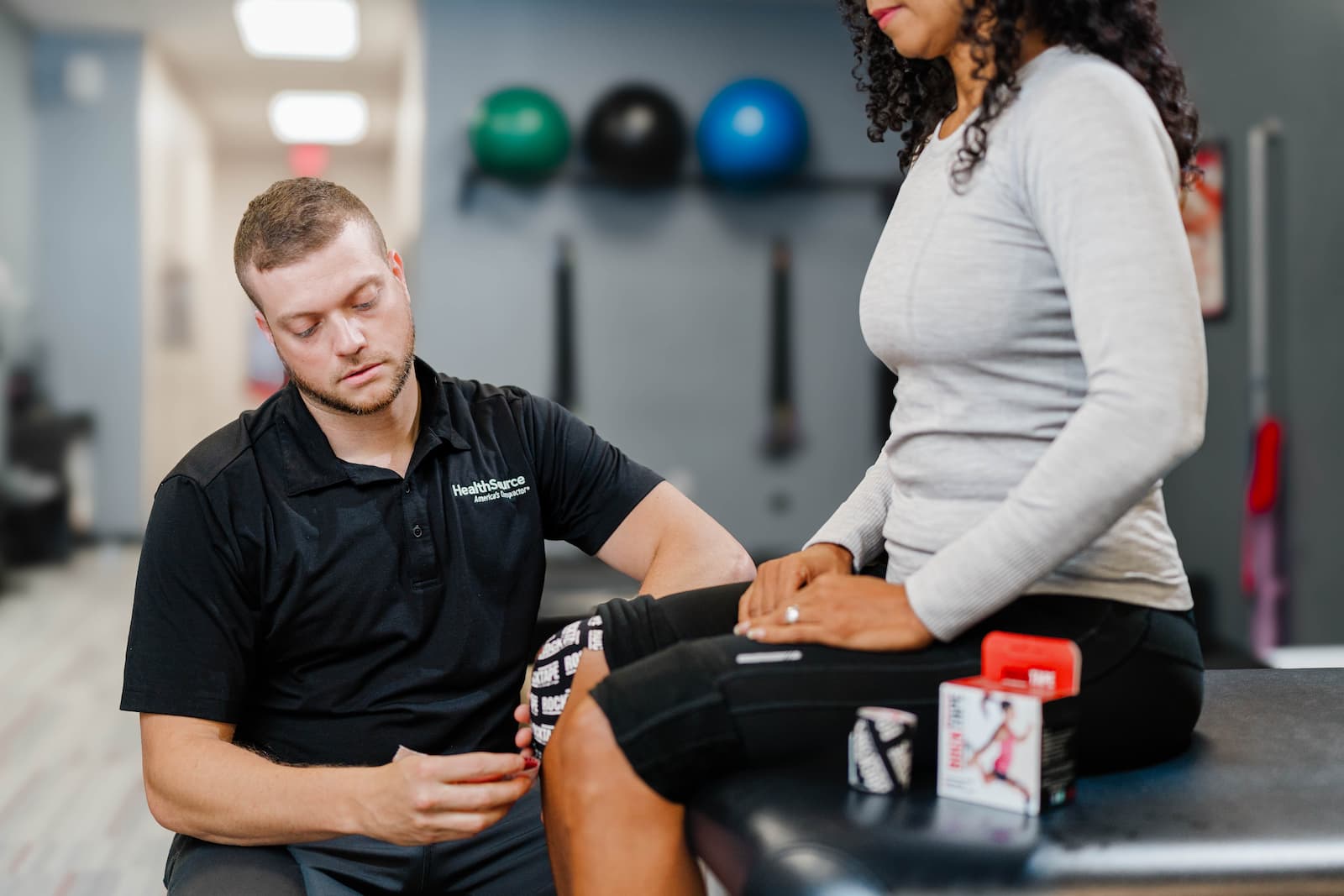 Close up of a practitioner placing tape on a patient's knee with careful precision.
