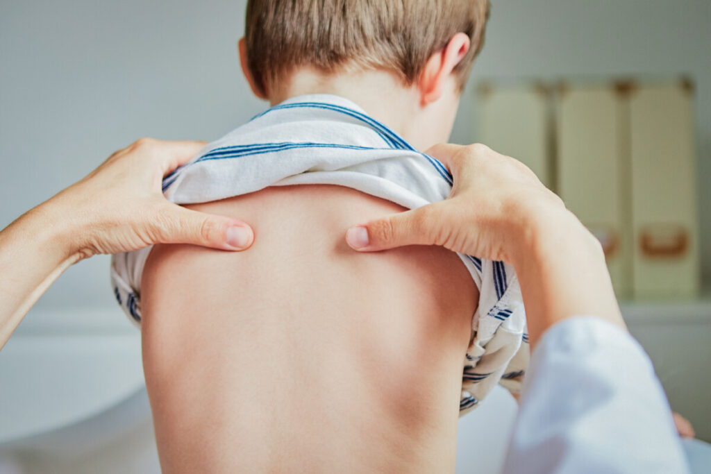 Chiropractor checking child's spine during School Physical Exam.