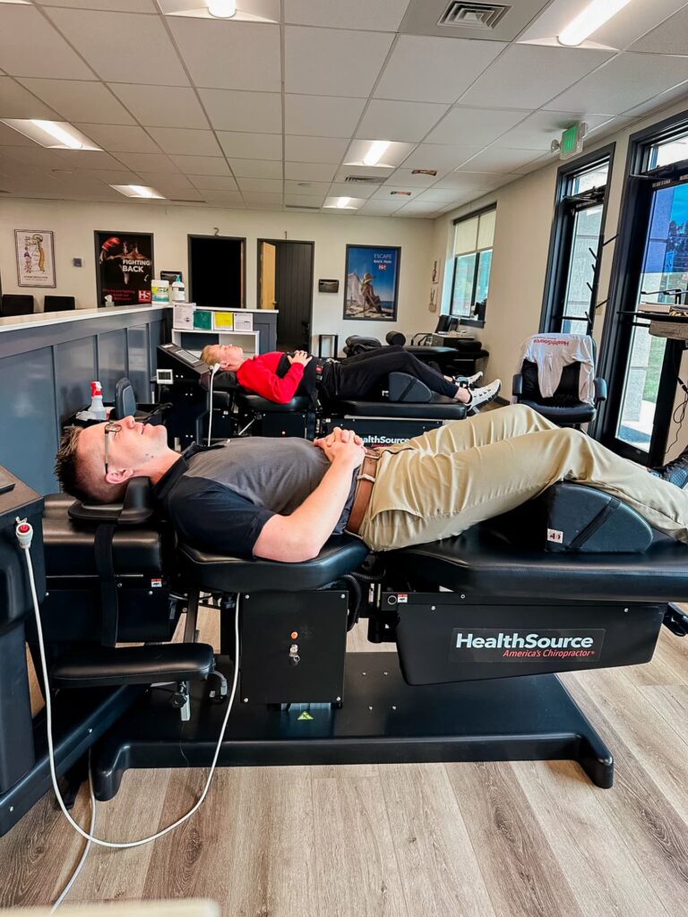 Side view of two patients laying side-by-side on spinal decompression tables.